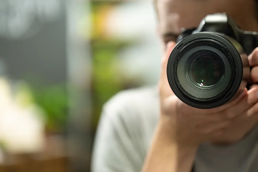 Reflection in the mirror of a man with a camera close up.