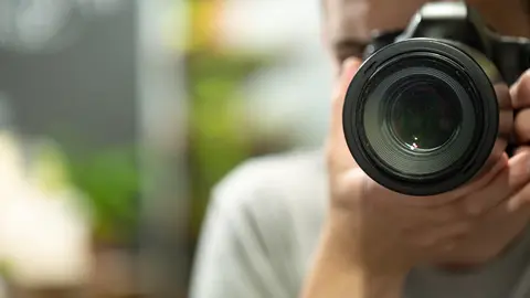 Reflection in the mirror of a man with a camera close up.